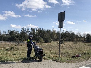 Policjant stoi przy rozbitym motorowerze