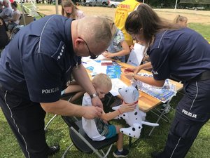 Policjant nakłada pieczątkę na ramie chłopca