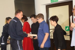 Fotografia przedstawia zaproszonych gości oraz policjantów rozdających nagrody uczestnikom konkursu.