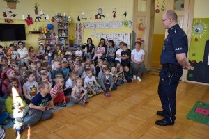 Policjant rozmawia z dziećmi które siedzą na podłodze