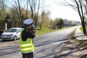 Na zdjęciu policjant wykonuje pomiar prędkości