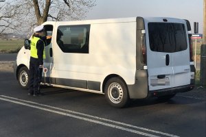 Fotografia przedstawia umundurowaną policjantkę ruchu drogowego podczas prowadzonej kontroli busa koloru białego.