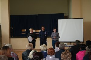 Fotografia przedstawia umundurowaną policjantkę stojącą w sali obok niej pracownica szkoły oraz przedstawicielka sanepidu. na pierwszym planie widać siedzących tyłem do zdjęcia rodziców.