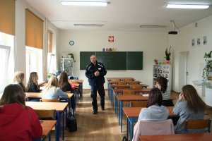 Zdjęcie przedstawia umundurowanego policjanta prowadzącego zajęcia dla siedzących przed nim uczniów.