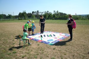 Zdjęcie przedstawia umundurowaną policjantkę prowadzącą grę edukacyjną dla dzieci.