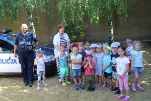 Zdjęcie przedstawia dzieci pozujące wspólnie z umundurowanym policjantem do zdjęcia.