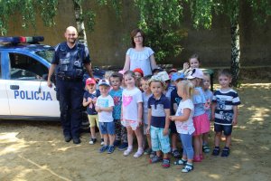 Zdjęcie przedstawia dzieci pozujące wspólnie z umundurowanym policjantem do zdjęcia.