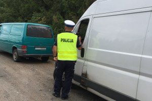 Zdjęcie przedstawia policjanta ruchu drogowego kontrolującego auto dostawcze