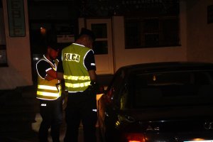 Zdjęcie przedstawia policjantów patrolowców kontrolujących pojazd osobowy