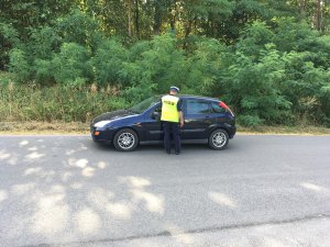 Policjant kontroluje kierującego pojazdem.