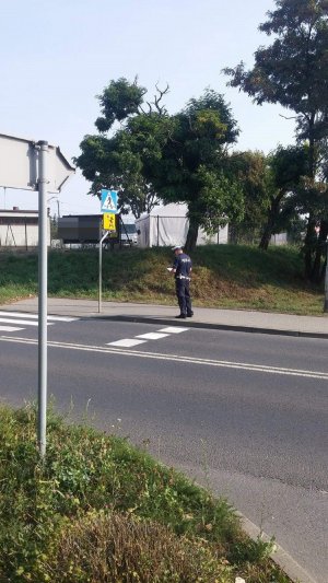 Policjant sprawdza usytuowanie znaków pionowych