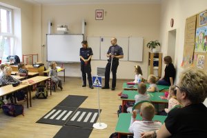 Zdjęcie przedstawia umundurowanych policjantów prowadzących zajęcia dla dzieci w sali lekcyjnej.