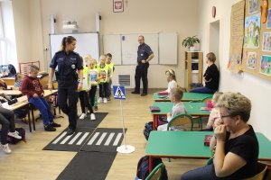 Zdjęcie przedstawia umundurowanych policjantów prowadzących zajęcia dla dzieci w sali lekcyjnej.