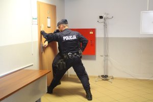 zdjęcie przedstawia dwóch umundurowanych policjantów stojących przy drzwiach gdzie zabarykadował się agresor wraz z zakładnikiem