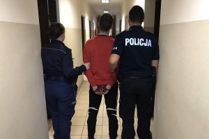 Zdjęcie przedstawia umundurowanych policjantów prowadzących zatrzymanego podejrzanego