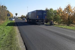 Zdjęcie przedstawia stojącą na drodze ciężarówkę oraz motocykl.