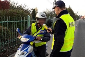 Zdjęcie przedstawia umundurowanego policjanta prowadzącego kontrolę trzeźwości motorowerzysty