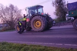 Zdjęcie przedstawia umundurowanych policjantów prowadzących kontrolę trzeźwości kierowcy ciągnika rolniczego.