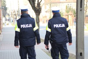 Zdjęcie przedstawia umundurowanych policjantów idących chodnikiem.