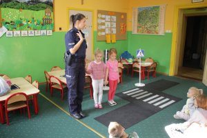 Zdjęcie przedstawia policjantkę uczącą dzieci przepisów drogowych. Obok policjantki dwie dziewczynki.