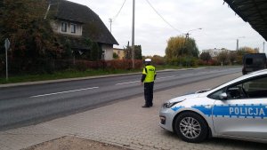 Zdjęcie przedstawia policjanta ruchu drogowego obserwującego ruch na drodze.