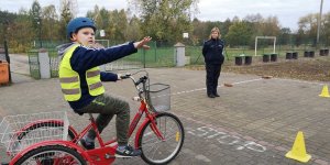 Zdjęcie przedstawia chłopca egzaminowanego na kartę rowerową. w tle widać umundurowaną policjantkę.