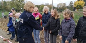 Zdjęcie przedstawia umundurowaną policjantkę składającą gratulacje uczestniczącym w egzaminie dzieciom.