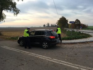 Zdjęcie przedstawia umundurowanych policjantów ruch drogowego kontrolujących pojazd osobowy