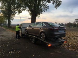 Zdjęcie przedstawia umundurowanych policjantów ruch drogowego kontrolujących pojazd - lawetę