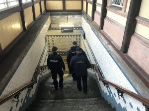 Zdjęcie przedstawia policjantów wspólnie z pracownikami Służby Ochrony Kolei kontrolujących tunel podziemny na dworcu kolejowym