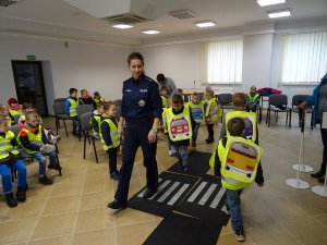 Zdjęcie przedstawia umundurowaną policjantkę, która w świetlicy jednostki prowadzi zajęcia z ruchu drogowego dla dzieci.