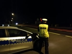 Zdjęcie przedstawia umundurowanego policjanta prowadzącego obserwację ruchu pojazdów