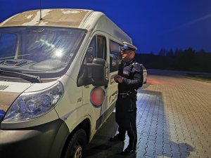 Zdjęcie przedstawia umundurowanego policjanta prowadzącego kontrolę pojazdu