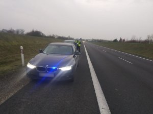 Zdjęcie przedstawia umundurowanego policjanta prowadzącego kontrolę pojazdu