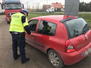 Zdjęcia przedstawia policjanta ruchu drogowego kontrolującego pojazd osobowy