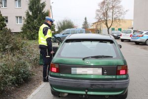 Zdjęcie przedstawia umundurowanego policjanta ruchu drogowego kontrolującego pojazd osobowy