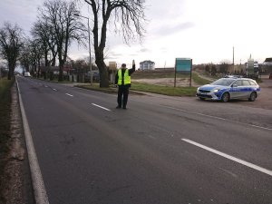 Zdjęcie przedstawia umundurowanego policjanta zatrzymującego do kontroli pojazd