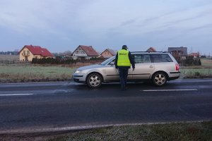 Zdjęcie przedstawia umundurowanego policjanta sprawdzającego trzeźwość kierowcy auta osobowego