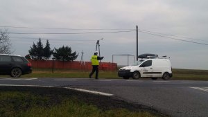 Zdjęcie przedstawia umundurowanego policjanta ruchu drogowego zatrzymującego do kontroli auto