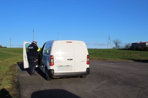 Zdjęcie przedstawia umundurowanego policjanta ruchu drogowego kontrolującego auto