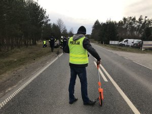 Zdjęcie przedstawia technika kryminalistyki prowadzącego czynności oględzin na miejscu wypadku