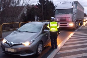 Zdjęcie przedstawia umundurowaną policjantkę ruchu drogowego prowadzącą kontrolę stanu trzeźwości kierowców