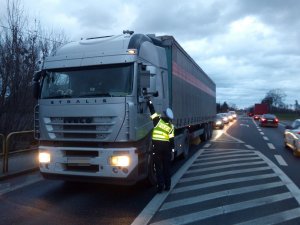 Zdjęcie przedstawia umundurowaną policjantkę ruchu drogowego prowadzącą kontrolę stanu trzeźwości kierowców