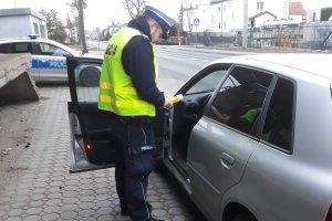 Zdjęcie przedstawia policjanta ruchu drogowego kontrolującego trzeźwość kierowców