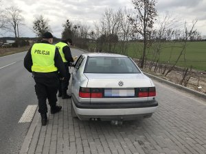 Zdjęcie przedstawia umundurowanych policjantów prowadzących kontrole drogową.