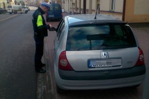 Zdjęcie przedstawia umundurowanego policjanta prowadzącego kontrolę pojazdu