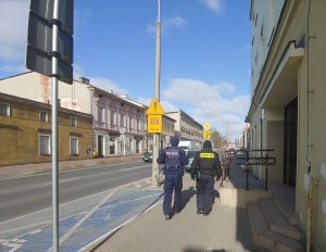 Zdjęcie przedstawia policjanta i strażnika miejskiego prowadzącego wspólny patrol