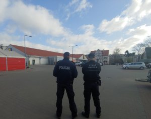 Zdjęcie przedstawia policjanta i strażnika miejskiego prowadzącego wspólny patrol