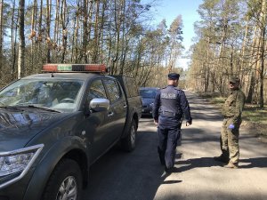 Zdjęcie przedstawia policjanta i strażnika leśnego wspólnie kontrolujących tereny leśne