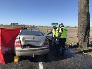 Zdjęcie przedstawia miejsce wypadku i pracujących na miejscu zdarzenia policjantów